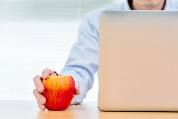 Man at laptop holding red apple