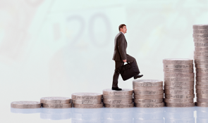 Businessman walking up a stack of large coins
