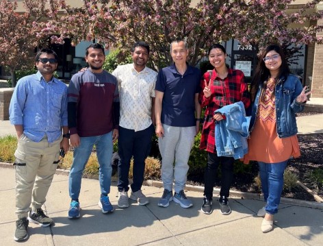 A group of people standing on a sidewalk.