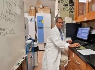 Hussein Shimelis stands at a computer in a small lab