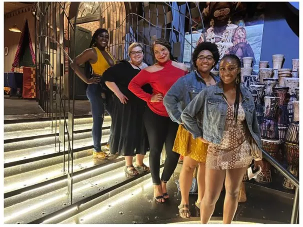 Joelle poses with her research group on the stairs in a restaurant.