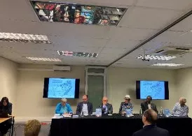 Panelists sit behind a table at the front of a room. 
