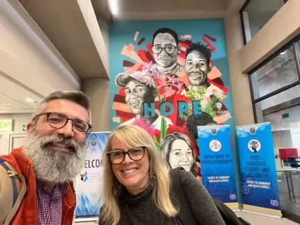 Tokac and Chipps in front of a "Hope" mural inside a building.