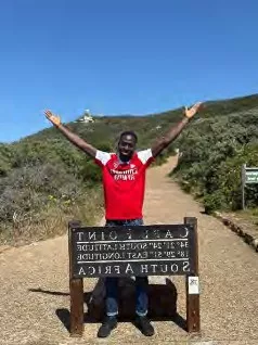 Abeeb poses behind the sign at Cape Point