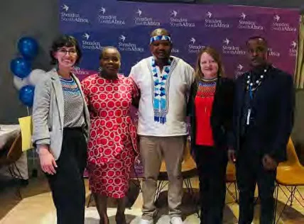 Five members of the NLA South Africa planning team pose in front of a purple Stenden SA backdrop