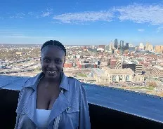 Asemahle poses at the top of the WWI Memorial with the Kansas City skyline behind her