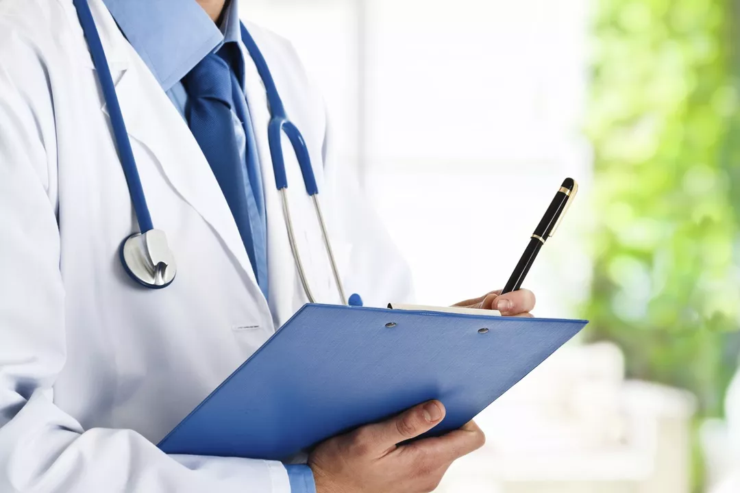 Close up of doctor in a lab coat holding a clip board and pen, stethoscope around their neck.