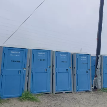 A row of five blue Sanitech portable toilets